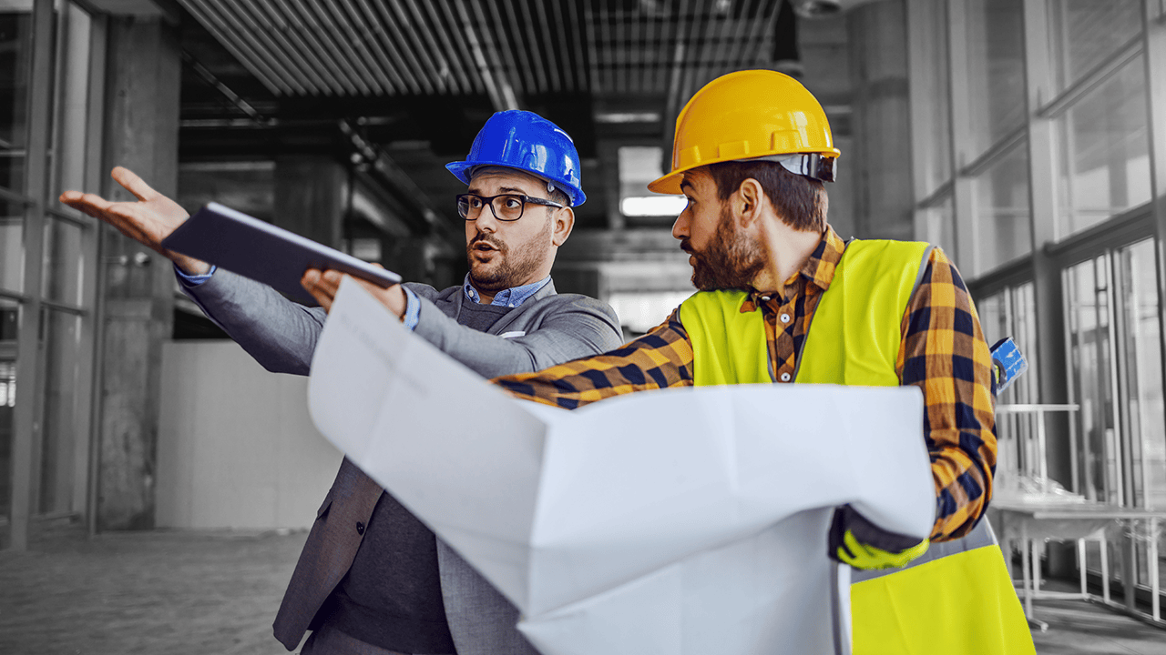 How to Eliminate Data Entry Errors in Plumbing Design An engineer and site worker reviewing drawings on a construction site — illustrating the cost of identifying plumbing design errors after work has begun